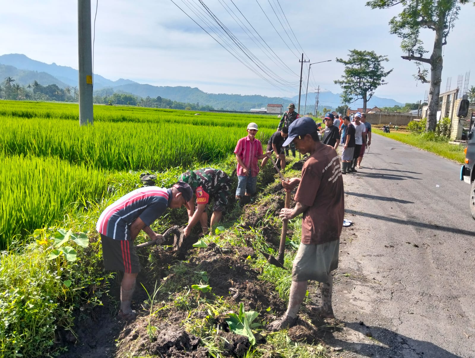 Suasana semangat kerja bakti membersihkan saluran air di sepanjang jalan perbatasan Desa Bayem dan Sukosari, Kasembon. Tampak puluhan personel Koramil dan warga masyarakat bahu-membahu mengerjakan tugasnya di bawah terik matahari.